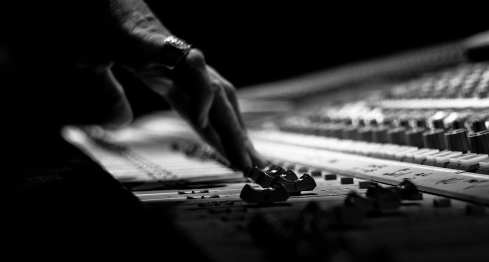 A hand riding a fader on the console at Orbit Audio, a Seattle recording studio